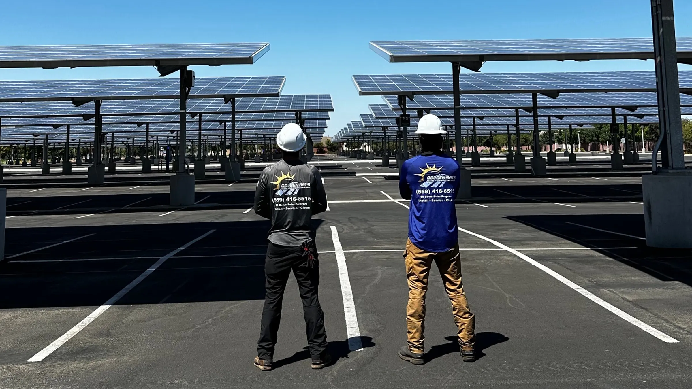 Golden Rays solar panel cleaning crew in Fresno, CA standing beneath the Fresno State carport array in branded shirts and hard hats