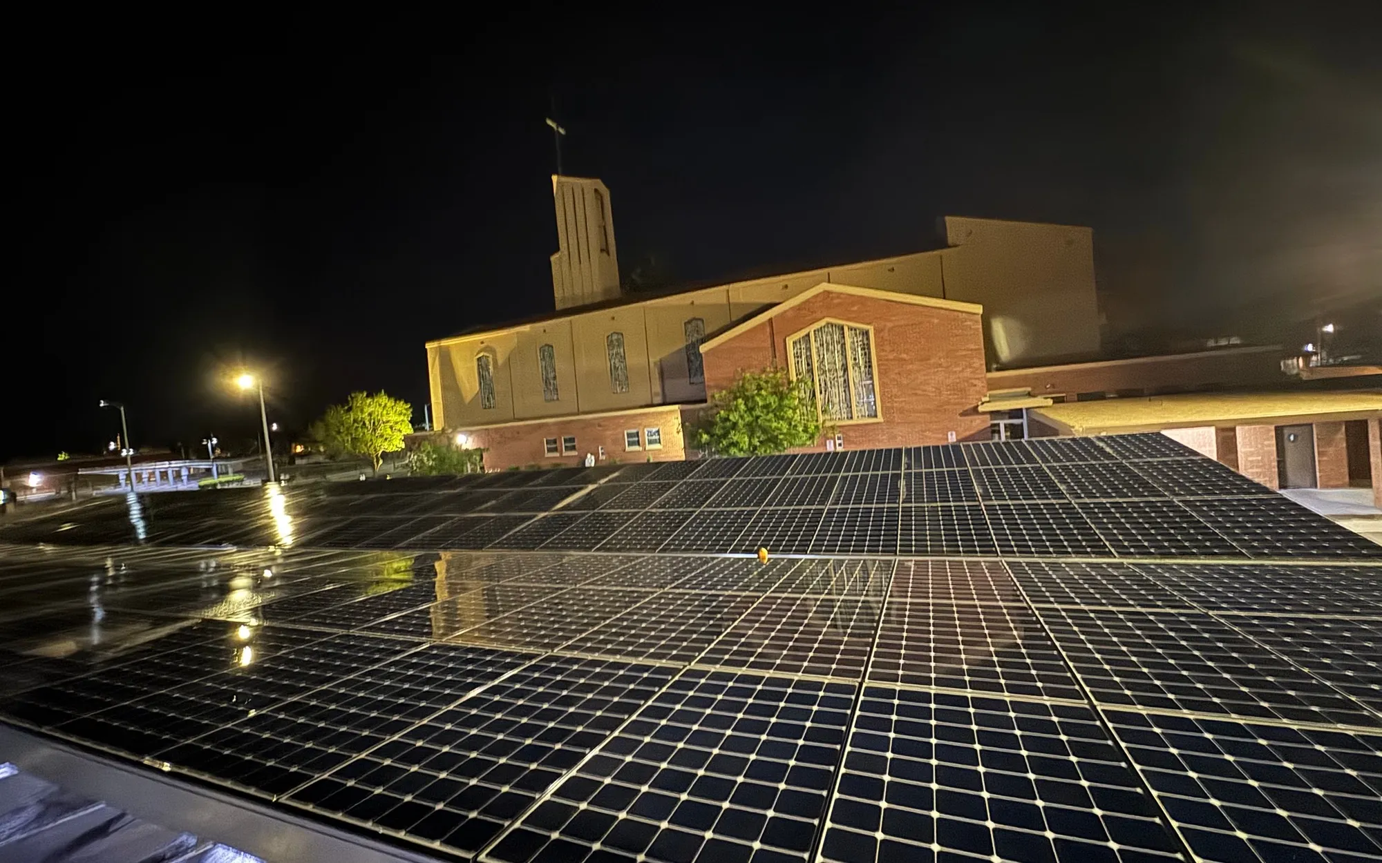 Night solar panel cleaning at St. Joachim Church in Madera, CA. Freshly washed panels in front of the lit church by Golden Rays